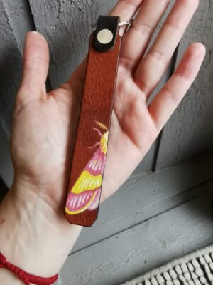 Porte clés Anisote de l'Érable, en cuir marron peint à la main. L'anisote est un papillon rose et jaune