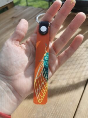 Porte clés cigale. Cuir orange et motif de demi cigale peint à la main. La cigale est tuquoise avec les ailes et les yeux jaunes