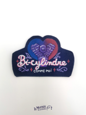 Patch en cuir peint à la main. Un moteur bicylindre est peint sur un fond en forme de coeur au dégradé couleurs du drapeau bisexuel : bleu violet et rose. Devant l'illustration le texte "bi-cylindre" écrit dans une typographie un peu rétro